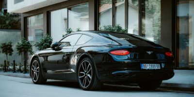 Rear side view of a sleek black Bentley coupe, a model renowned for its powerful W12 engine and refined performance.