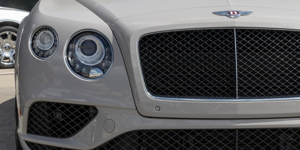 Front view of a luxurious white Bentley showcasing its bold grille design, powered by the iconic W12 engine.