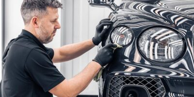 Skilled technician polishing a Bentley headlight, emphasizing the quality and precision associated with Bentley maintenance cost.