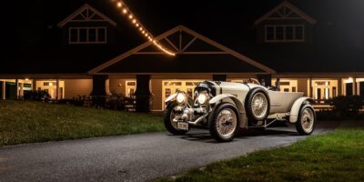 Vintage Bentley car parked under string lights at night with clear view of bentley logo on grille, symbolizing classic car logo with wings.