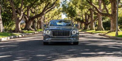 Front view of 2026 Bentley Flying Spur luxury sedan parked on a tree lined residential street in daylight